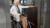 Mature woman in glasses on disabled carriage using elevator