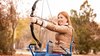 Young woman in wheelchair practicing archery outdoors